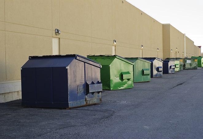 a construction worker unloading debris into a blue dumpster in Abbottstown PA